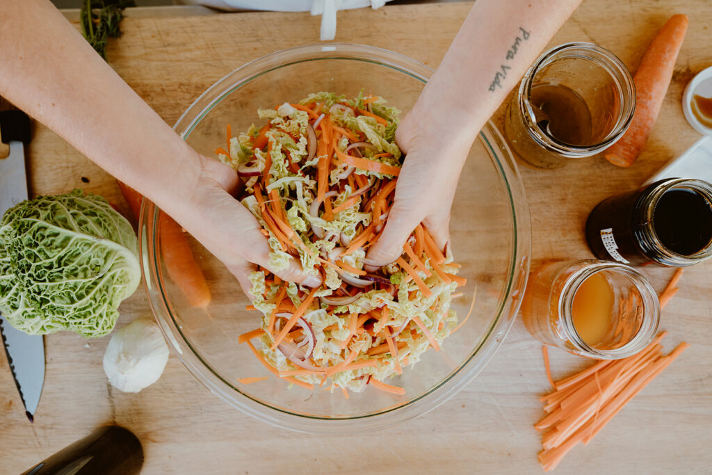 Mixing the simple cabbage and carrot salad by hand.
