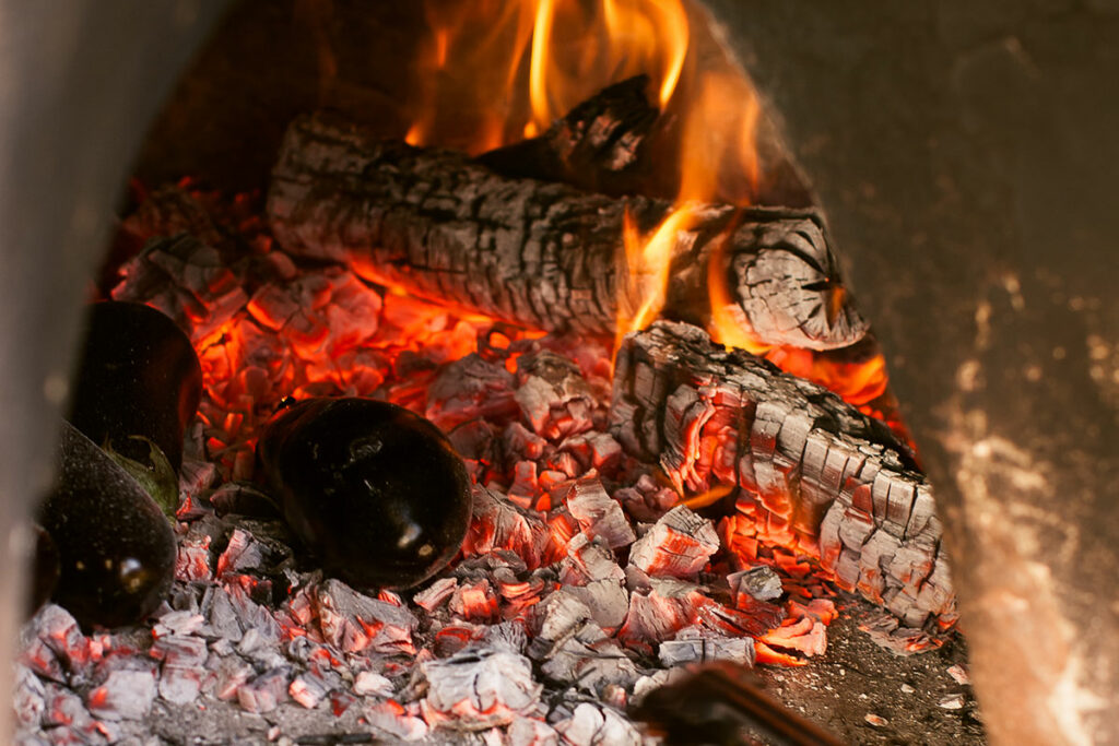 Eggplant being cooked in a fireplace.