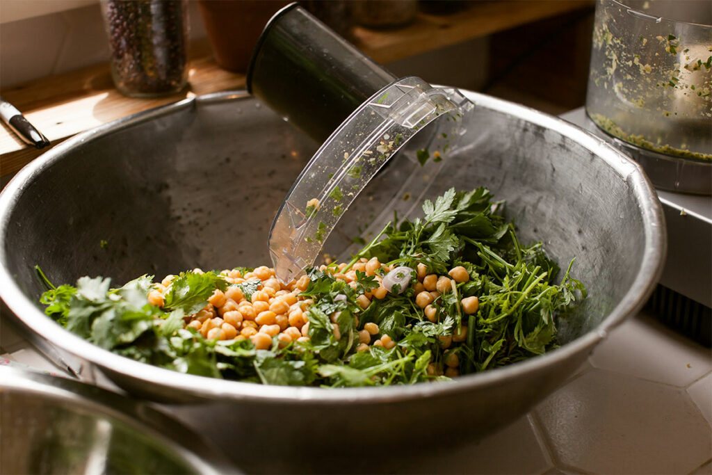 Baby greens and spring vegetables with green goddess dressing in large metal bowl.