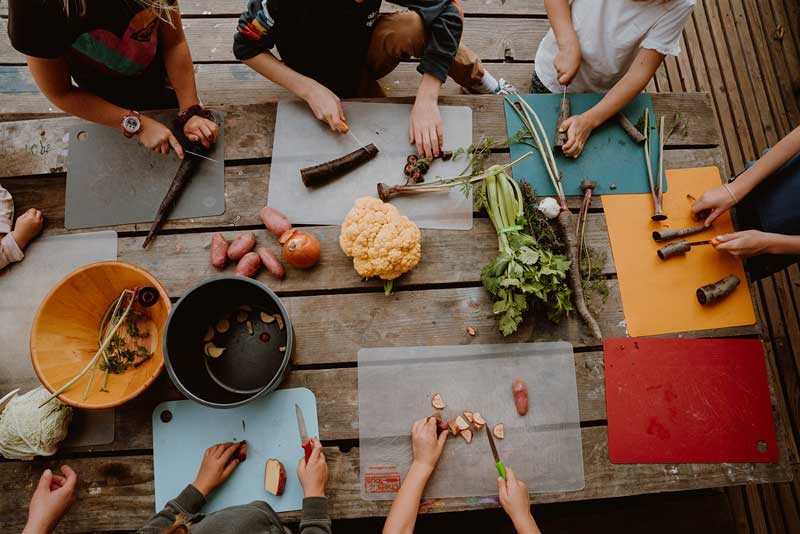 Children gathered around table prepping veggies.