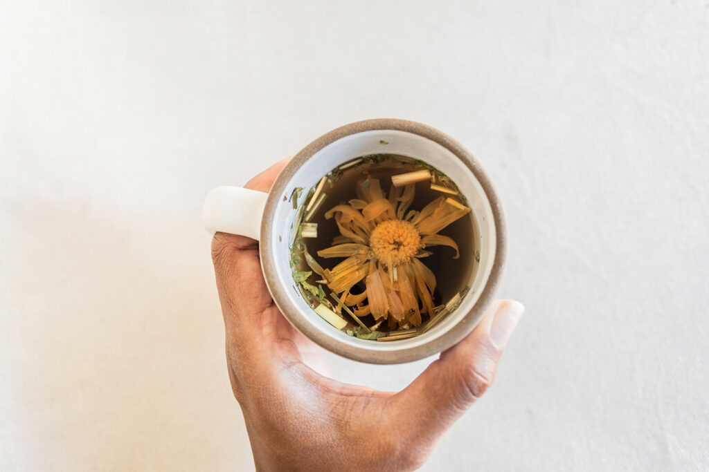 Hand holding mug of chamomile tea