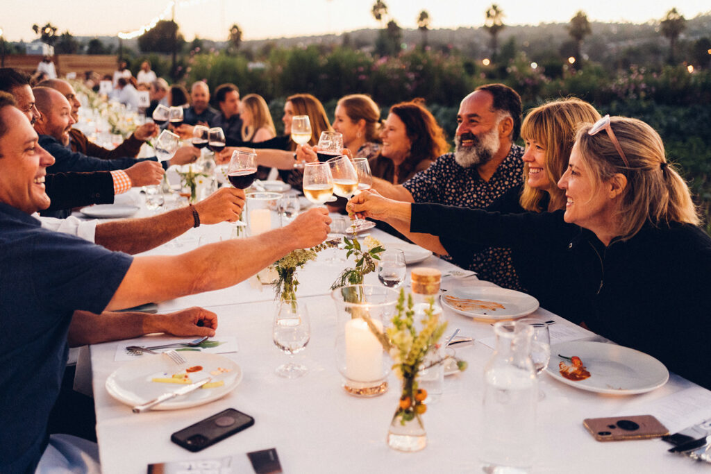 People raising glasses to cheers at dinner table.