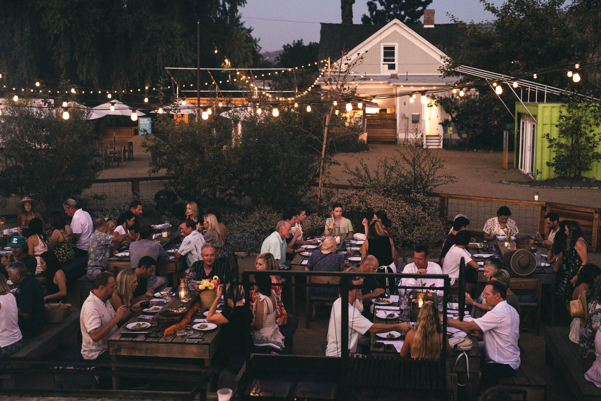 Community Table dinner with guests sitting at picnic tables