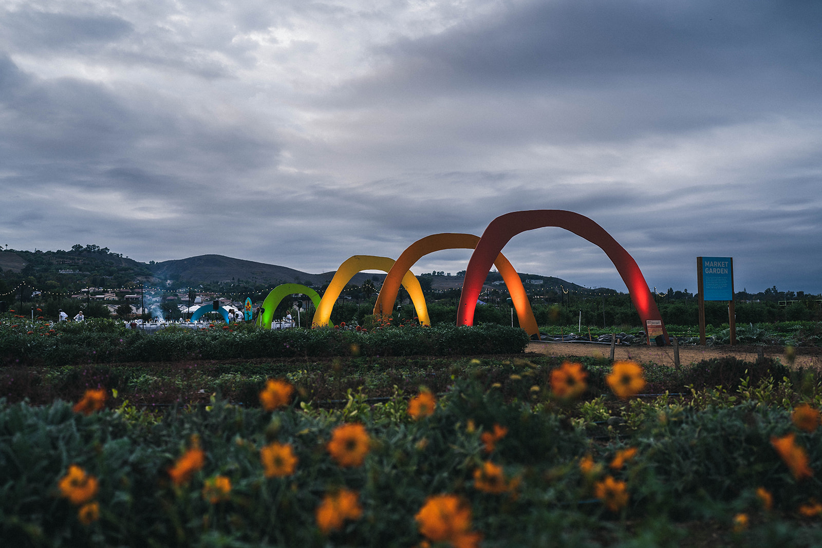 Rainbow sculpture in the field with a cloudy sky