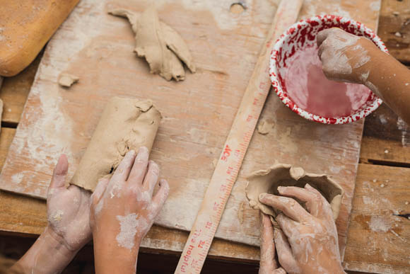 kids hands making ceramic bowls and cups