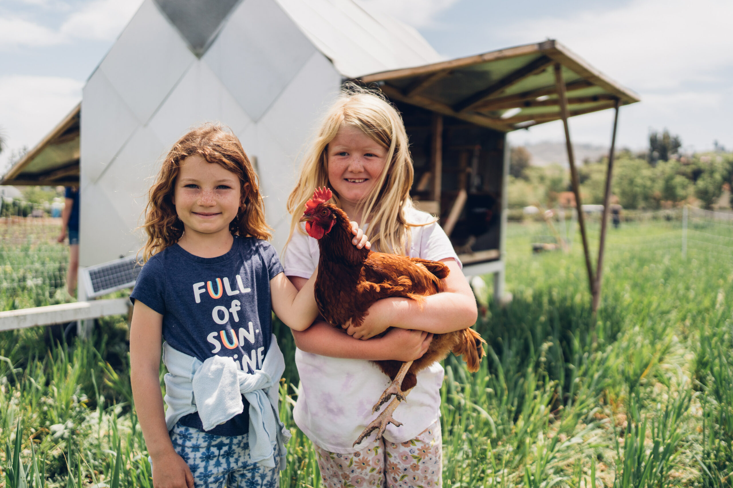 two girls in front of chicken coop