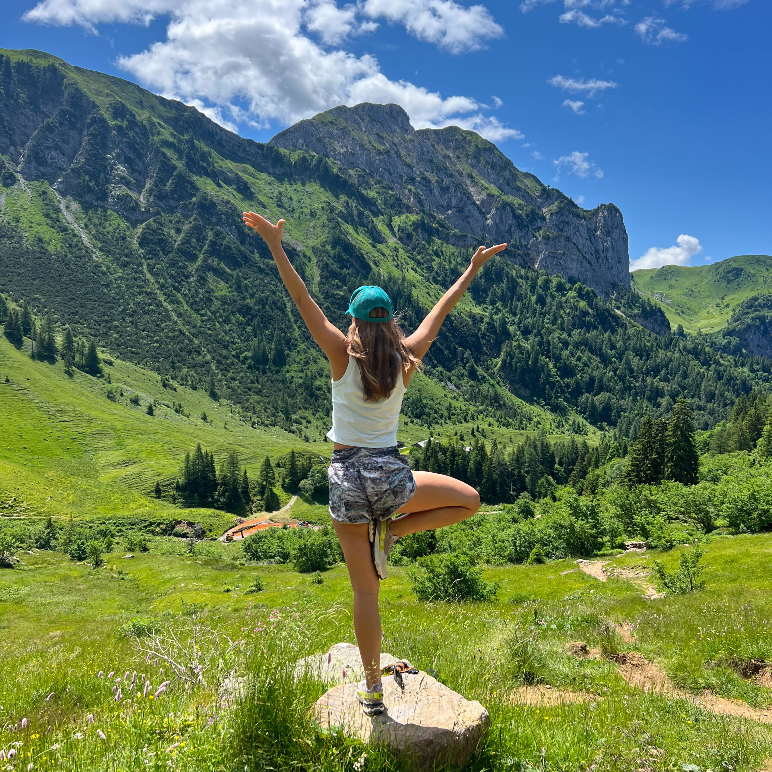 Yoga teacher in tree pose facing a mountain valley in Italy