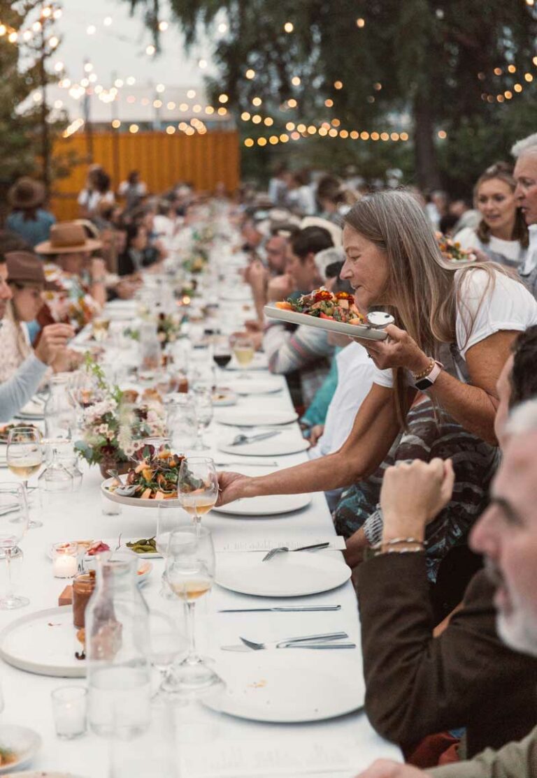 Server places plate on long white table at Green Feast 2023.
