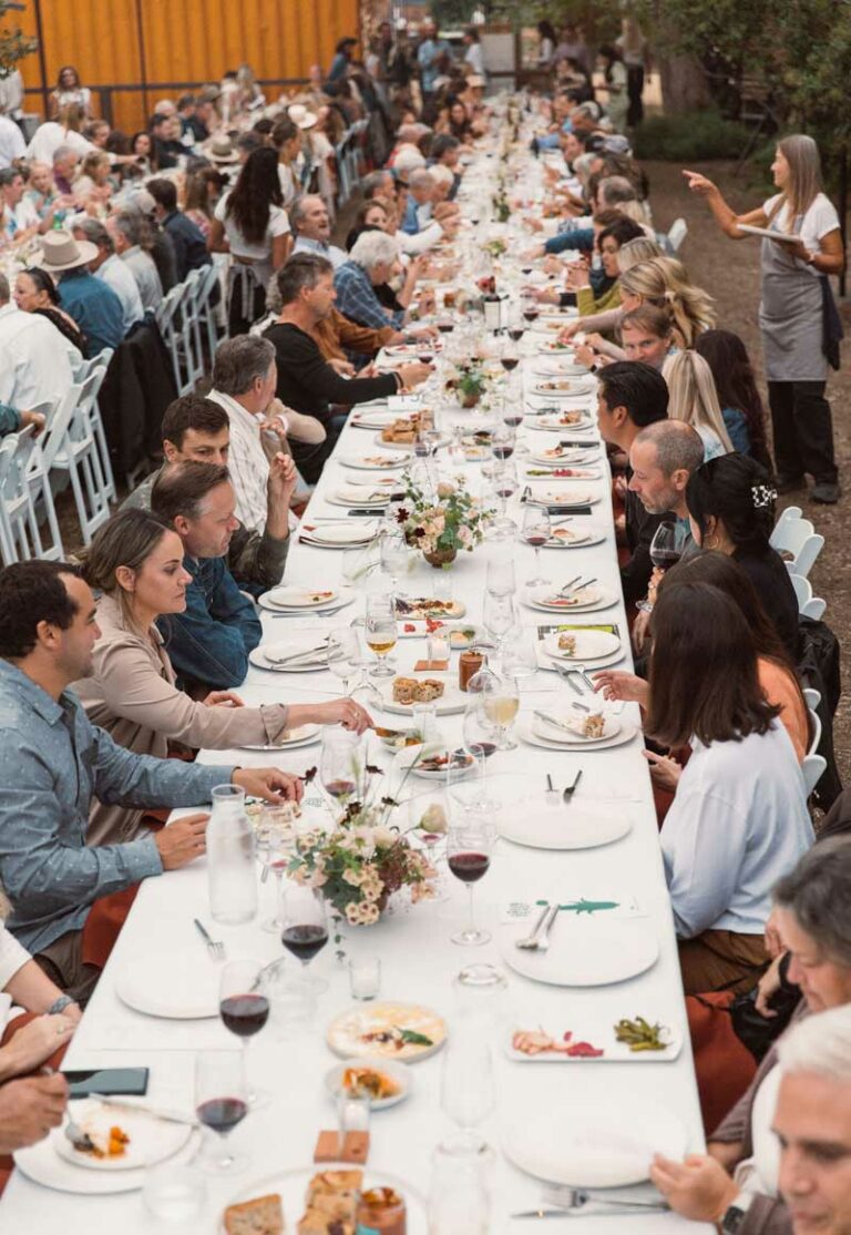 Guests seated at a long table with white table cloth.