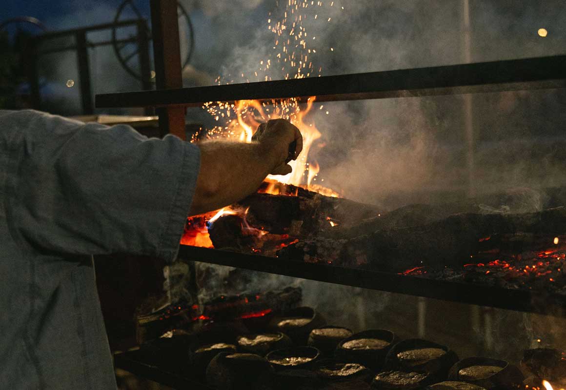 Chef prepares food over an open flame.