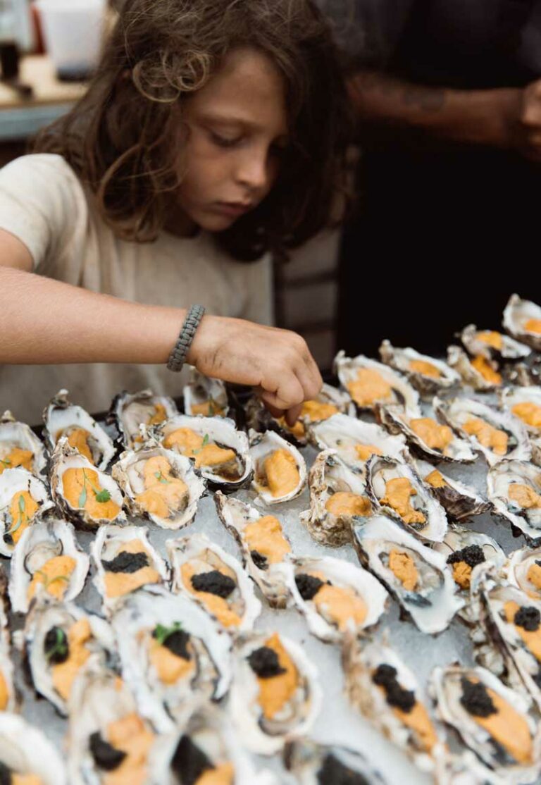 Boy examines table of oysters.